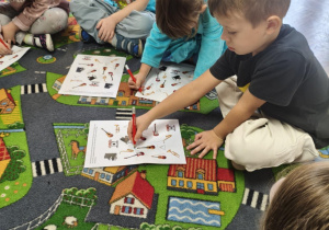 Dzieci wykonują zadanie na karcie pracy.