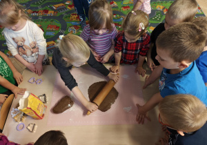 Dzieci rozwałkowują ciasto na pierniczki.