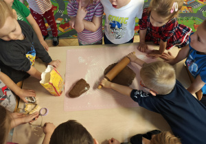 Dzieci rozwałkowują ciasto na pierniczki.