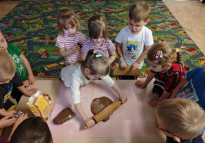 Dzieci rozwałkowują ciasto na pierniczki.
