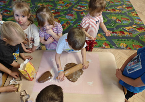 Dzieci rozwałkowują ciasto na pierniczki.