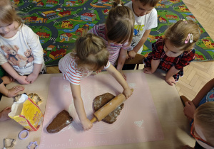 Dzieci rozwałkowują ciasto na pierniczki.