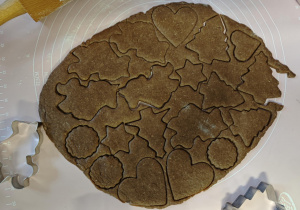 Na stolnicy jest rozwałkowane ciasto i wykrojone pierniki.