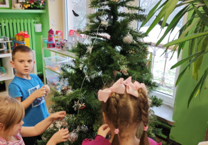 Dzieci wieszają bąbki na choince.