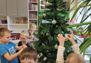 Dzieci wieszają bąbki na choince.