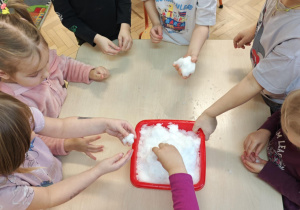 Dzieci poprzez dotyk doświadczają własciwości śniegu.