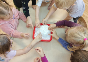 Dzieci poprzez dotyk doświadczają własciwości śniegu.