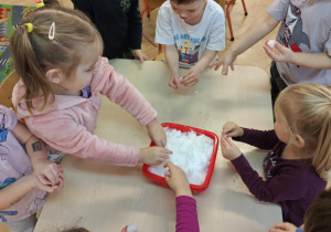 Dzieci poprzez dotyk doświadczają własciwości śniegu.