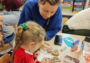 Dzieci wraz z Rodzicami ozdabiają pierniczki na świąteczny kiermasz.