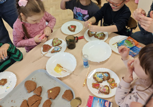 Dzieci wraz z Rodzicami ozdabiają pierniczki na świąteczny kiermasz.