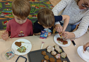 Dzieci wraz z Rodzicami ozdabiają pierniczki na świąteczny kiermasz.