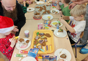 Dzieci wraz z Rodzicami ozdabiają pierniczki na świąteczny kiermasz.