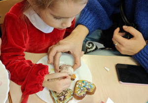 Dzieci wraz z Rodzicami ozdabiają pierniczki na świąteczny kiermasz.