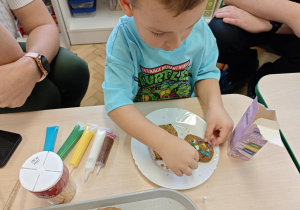 Chłopiec ozdabia pierniczki na świąteczny kiermasz.