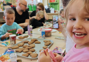 Dzieci wraz z Rodzicami ozdabiają pierniczki na świąteczny kiermasz.