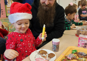 Dzieci wraz z Rodzicami ozdabiają pierniczki na świąteczny kiermasz.