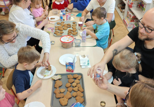 Dzieci wraz z Rodzicami ozdabiają pierniczki na świąteczny kiermasz.