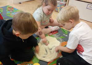Dzieci w ryżu odwzorowują odszukane w nim figury geometryczne.