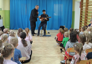 Pan Witek wyjaśnia dzieciom czym się gra na strunach mandoliny.