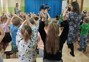 Dzieci klaszczą podczas słuchania wygrywanego utworu na gitarze elektrycznej.