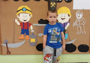 Dekoracja, a na jej tle chłopiec w czapce górnika.