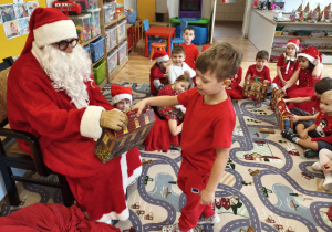 Mikołaj podczas wręczania prezentu dziecku
