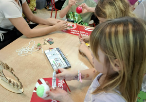 Rodzice i dzieci wykonują ozdoby świąteczne.