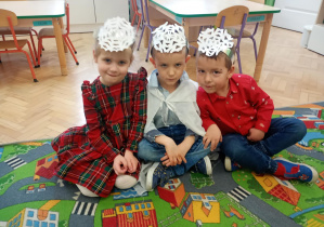 Dzieci siedzą na dywanie.