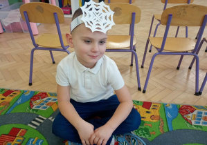 Chłopiec siedzi na dywanie.