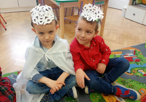 Dzieci siedzą w opaskach na dywanie.