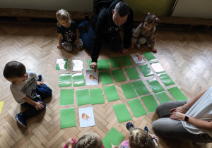 Tata grający z grupą dzieci w memory.