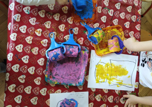 Dzieci malują farbami używając wzorzystch wałków.