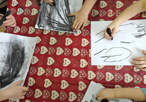 DZieci malują węglem drzewnym.