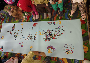 Dzieci tworzą wzory z guzików.