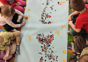 Dzieci tworzą zbiory żółtych guzików.