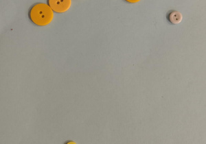 Dzieci tworzą wzory z guzików.