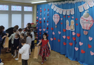 Dzieci niosą prezenty swoim dziadkom.