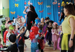 Dzieci z paniami tworzą karnawałowy pociąg.