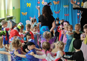 Dzieci z paniami tworzą karnawałowy pociąg.