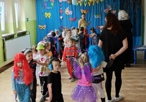 Dzieci z paniami tworzą karnawałowy pociąg.