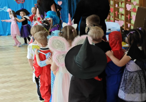 Dzieci z paniami tworzą karnawałowy pociąg.