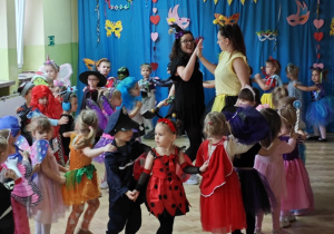 Dzieci z paniami tworzą karnawałowy pociąg.