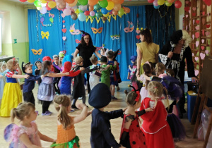 Dzieci z paniami tworzą karnawałowy pociąg.