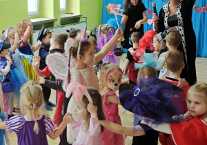 Dzieci z paniami tworzą karnawałowy pociąg.