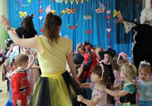 Dzieci z paniami tworzą karnawałowy pociąg.