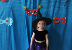 Dziewczynka w stroju czarownicy pozuje do zdjęcia.