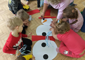 Dzieci układają postać bałwanka z elementów.