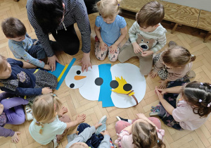 Dzieci układają postać bałwanka z elementów.