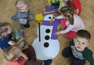 Dzieci układają postać bałwanka z elementów.