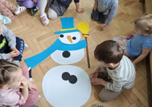 Dzieci układają postać bałwanka z elementów.